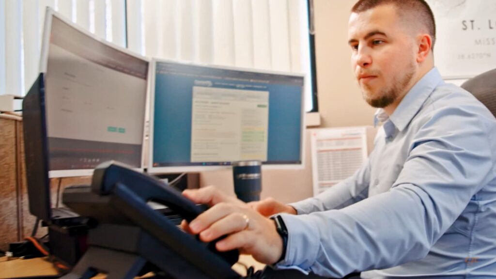 Person on the telephone also working on a dual screen monitor