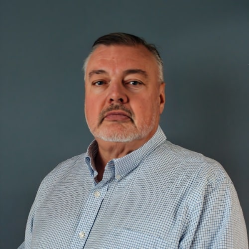 Man with a beard and blue checked shirt posing for a picture