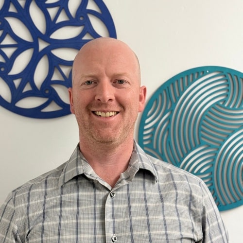 Tom, man in a gray plaid shirt posing for a picture